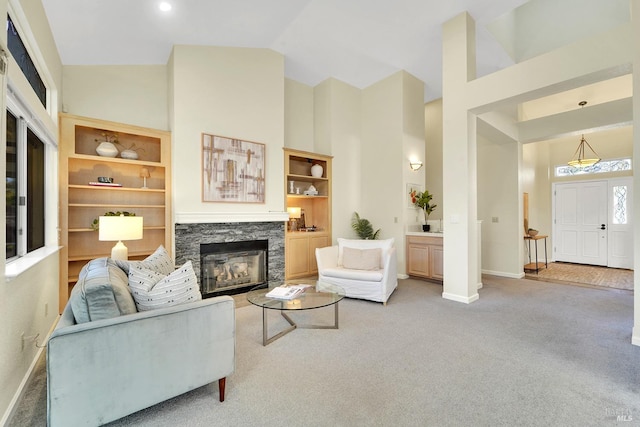 carpeted living room featuring a fireplace, built in shelves, and high vaulted ceiling