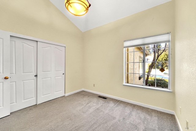 unfurnished bedroom with carpet, a closet, multiple windows, and lofted ceiling