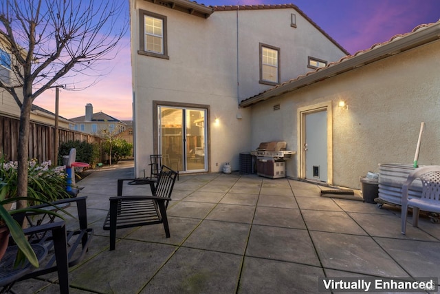 back house at dusk featuring a patio