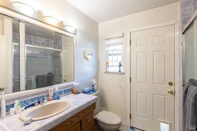 bathroom featuring vanity, toilet, and a shower with door