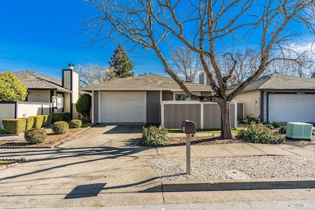 view of front of home with a garage, driveway, a fenced front yard, and cooling unit