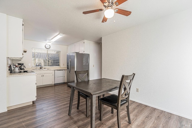 dining room featuring dark wood-type flooring, a textured ceiling, baseboards, and a ceiling fan