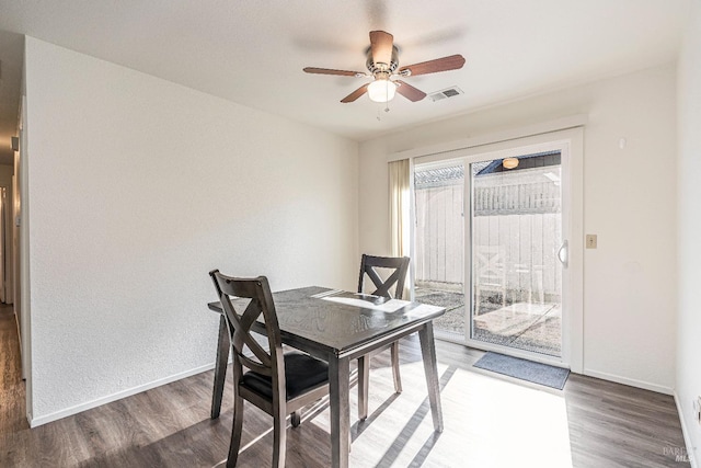 dining room featuring baseboards, visible vents, ceiling fan, and wood finished floors