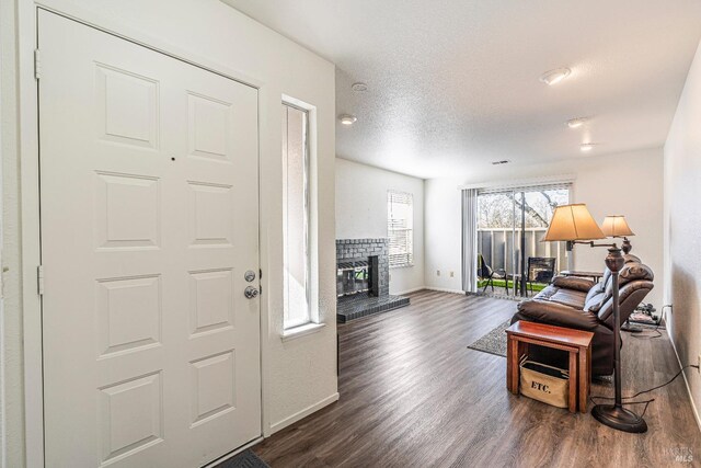 interior space featuring dark wood-style floors, a textured ceiling, a fireplace, and baseboards