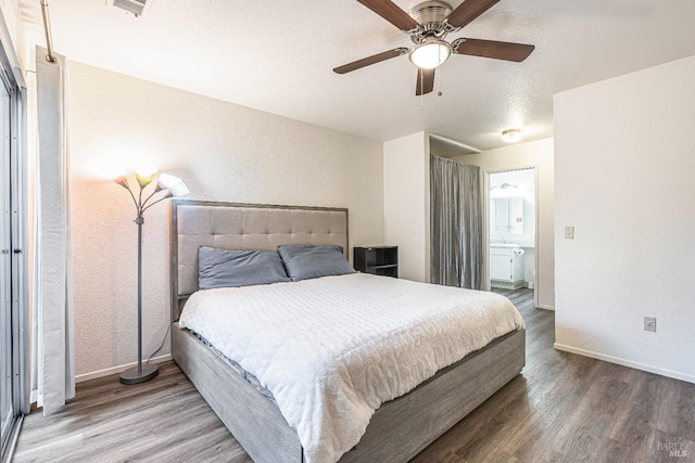 bedroom featuring baseboards, a ceiling fan, ensuite bath, wood finished floors, and a textured ceiling