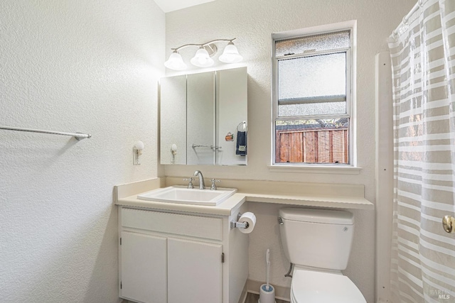 full bathroom featuring a textured wall, vanity, and toilet