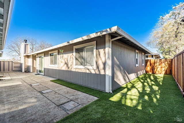 view of property exterior with a fenced backyard, a patio, and a lawn