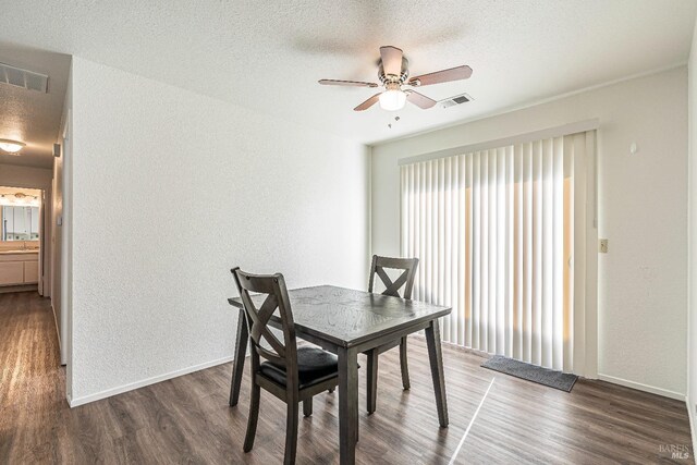 dining area featuring a textured ceiling, dark wood-type flooring, visible vents, and baseboards