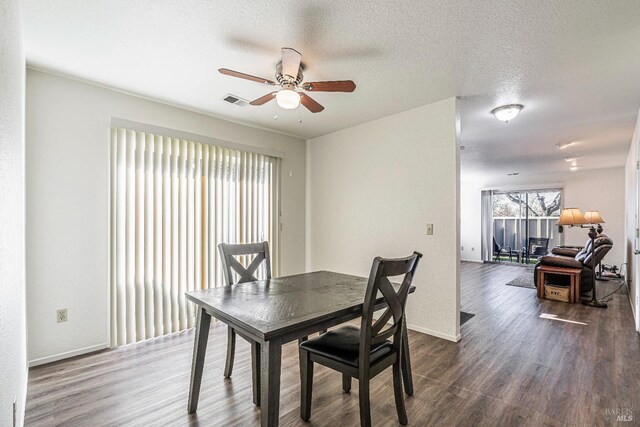 dining area featuring visible vents, a ceiling fan, a textured ceiling, wood finished floors, and baseboards