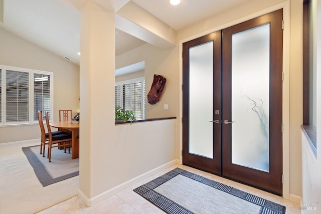 entryway featuring lofted ceiling, light tile patterned floors, and french doors