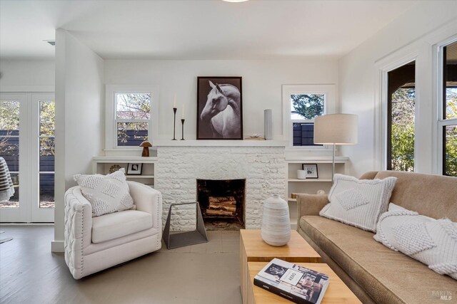 unfurnished living room with a stone fireplace, light hardwood / wood-style flooring, and french doors