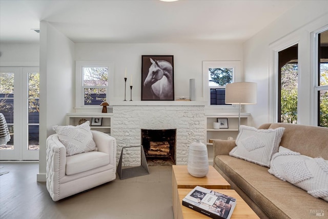 living room with a stone fireplace and wood finished floors