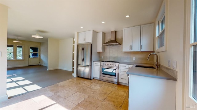 kitchen with a sink, white cabinets, light countertops, wall chimney range hood, and appliances with stainless steel finishes