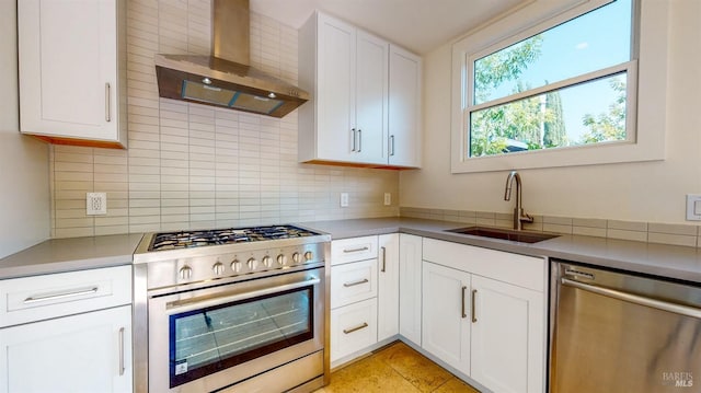 kitchen with a sink, white cabinetry, appliances with stainless steel finishes, wall chimney range hood, and decorative backsplash