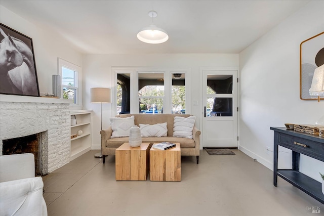 living area featuring finished concrete flooring, a fireplace, and baseboards