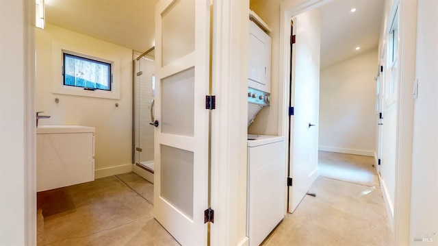 hall featuring recessed lighting, stacked washer / dryer, a sink, concrete flooring, and baseboards