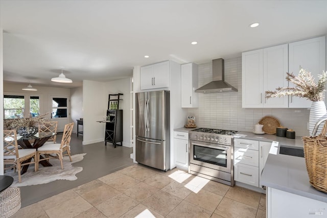 kitchen featuring white cabinetry, light countertops, appliances with stainless steel finishes, wall chimney range hood, and tasteful backsplash