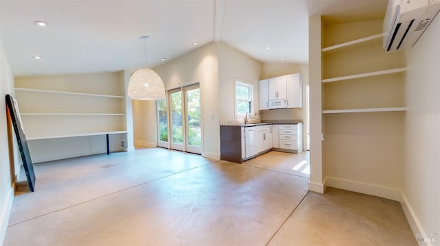 kitchen with finished concrete flooring, white cabinets, dark countertops, a wall unit AC, and hanging light fixtures