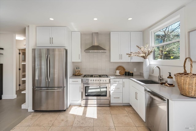 kitchen with decorative backsplash, appliances with stainless steel finishes, light countertops, wall chimney range hood, and a sink