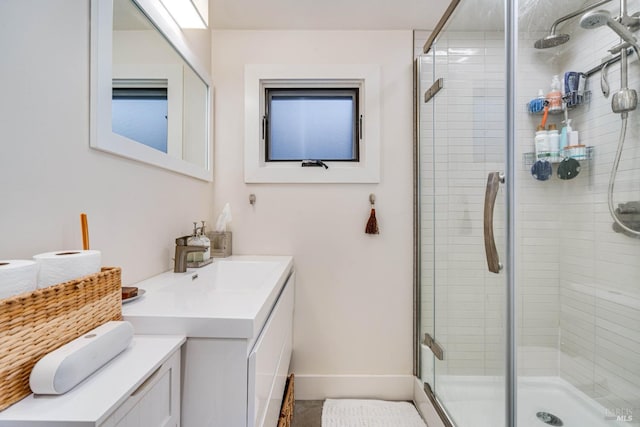 bathroom with a stall shower, baseboards, and vanity