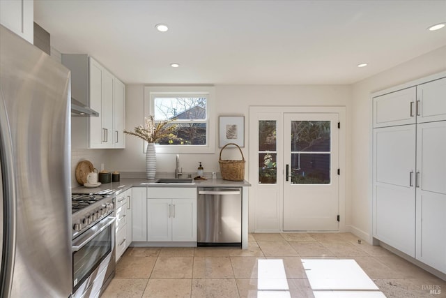 kitchen with recessed lighting, appliances with stainless steel finishes, white cabinetry, a sink, and under cabinet range hood