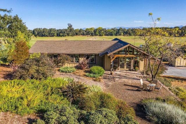 back of property with a rural view and french doors