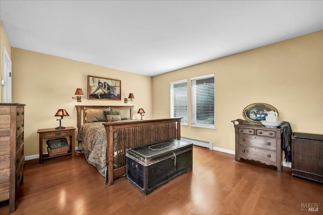 bedroom featuring baseboard heating and dark hardwood / wood-style flooring