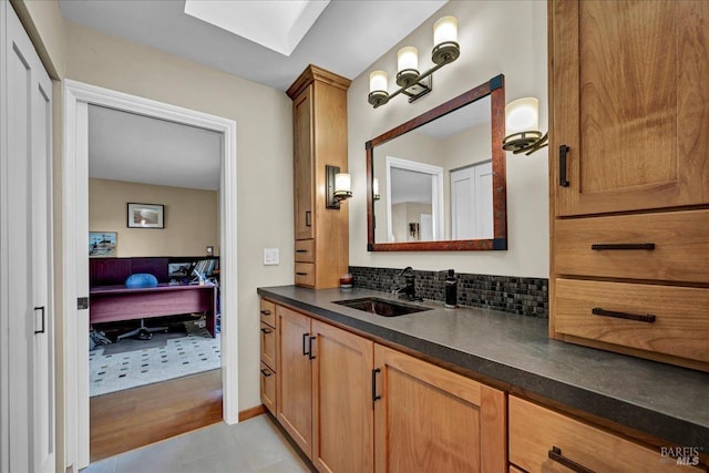 bathroom featuring tasteful backsplash, vanity, a skylight, and tile patterned flooring