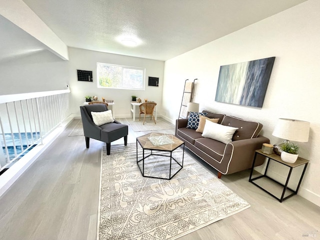 living room featuring lofted ceiling with beams, a textured ceiling, baseboards, and wood finished floors