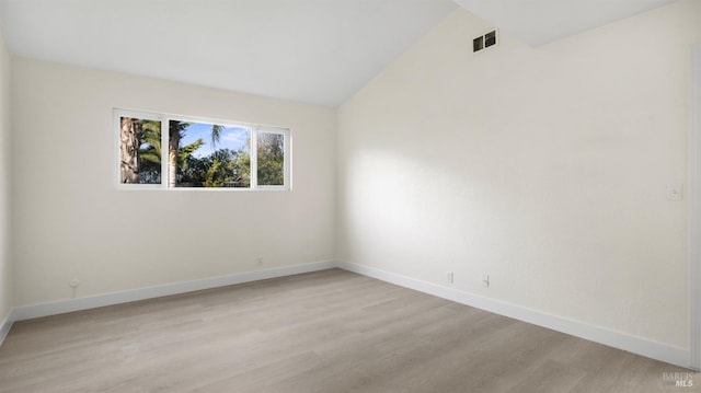 spare room featuring light wood-style floors, visible vents, vaulted ceiling, and baseboards