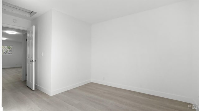 empty room featuring baseboards and light wood finished floors