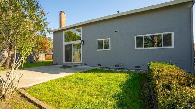 rear view of house with crawl space, fence, a lawn, and a patio