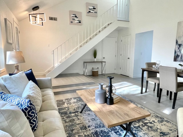 living room with stairs, high vaulted ceiling, visible vents, and baseboards