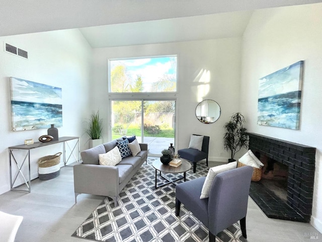 living room with a towering ceiling, a brick fireplace, baseboards, and visible vents