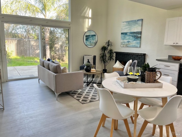 dining area with light wood-style flooring, a fireplace, and a high ceiling