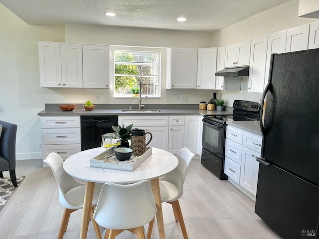 kitchen with a textured ceiling, under cabinet range hood, white cabinetry, light wood-style floors, and black appliances