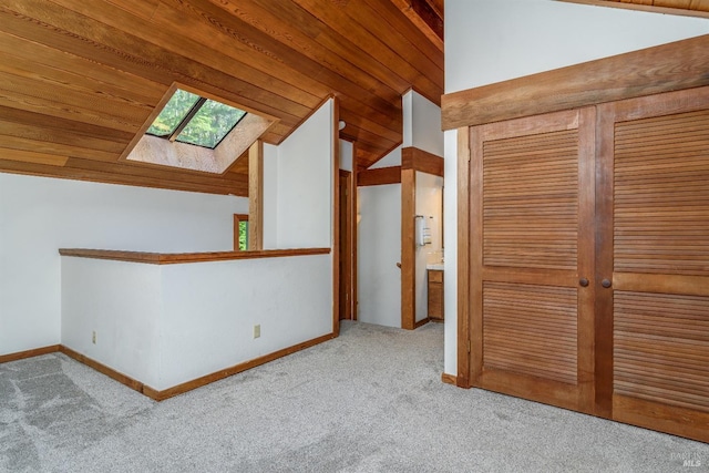 unfurnished bedroom with wood ceiling, baseboards, a closet, lofted ceiling with skylight, and carpet