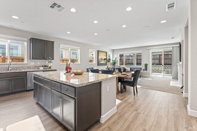 kitchen featuring visible vents, a kitchen island, dishwasher, recessed lighting, and a sink