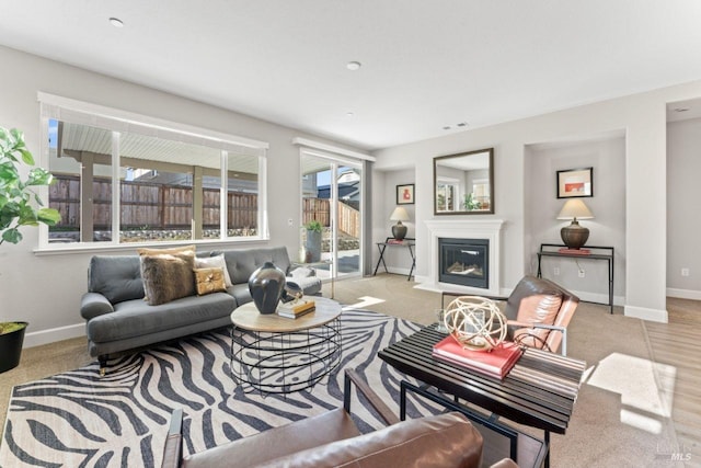 living area featuring baseboards, a fireplace with flush hearth, and visible vents