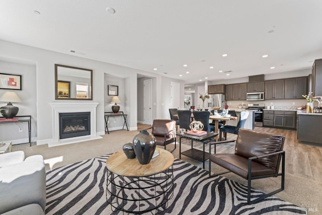 living room featuring a glass covered fireplace, recessed lighting, and baseboards