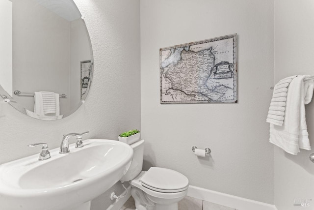 half bathroom with tile patterned flooring, toilet, baseboards, and a sink