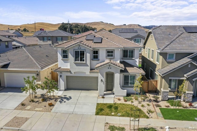 view of front of house with concrete driveway, a tiled roof, a residential view, and stucco siding