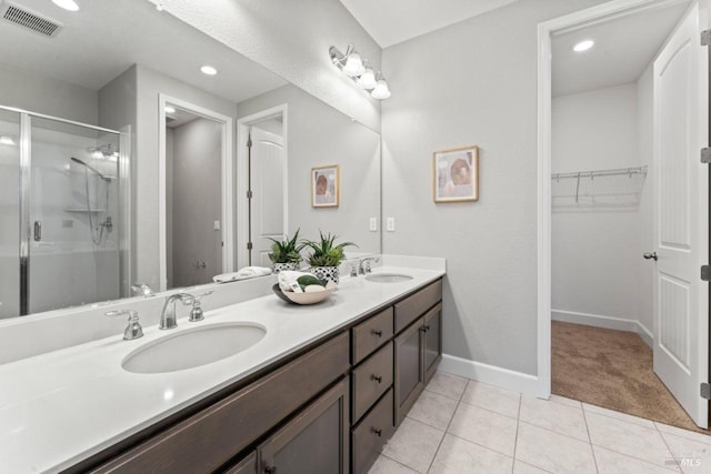 bathroom featuring double vanity, visible vents, a stall shower, and a sink