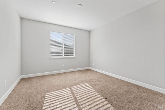 carpeted spare room featuring baseboards