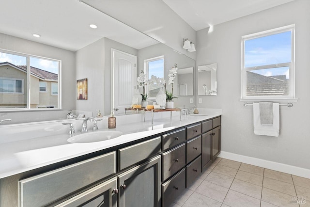 full bathroom with double vanity, tile patterned floors, baseboards, and a sink