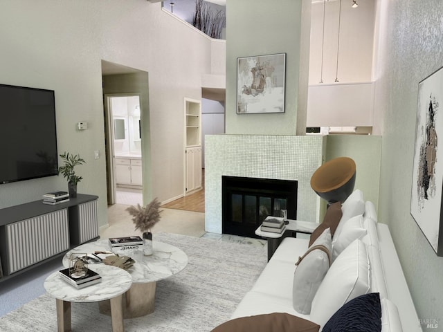 living room with a high ceiling and a tiled fireplace