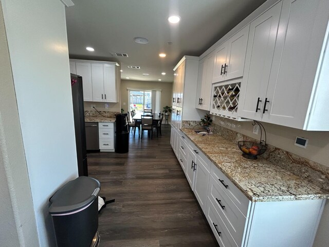 kitchen featuring stainless steel dishwasher, dark hardwood / wood-style floors, light stone countertops, and white cabinets