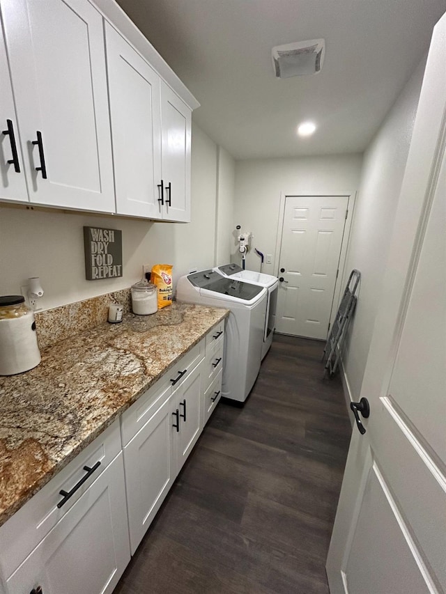 laundry area featuring cabinets, washer and dryer, and dark hardwood / wood-style flooring