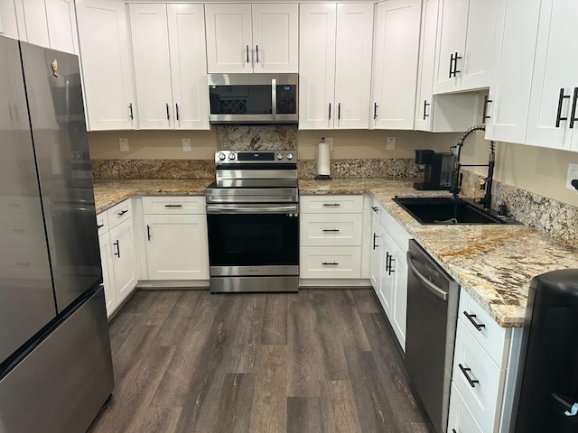 kitchen featuring dark hardwood / wood-style floors, white cabinetry, sink, stainless steel appliances, and light stone countertops