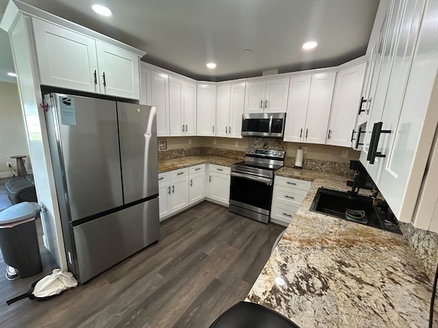 kitchen with sink, white cabinets, dark hardwood / wood-style flooring, stainless steel appliances, and light stone countertops